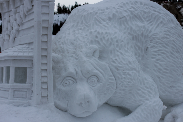 Schneekunst steht im Vordergrund mit einigen Bumen und dem Himmel im Hintergrund.