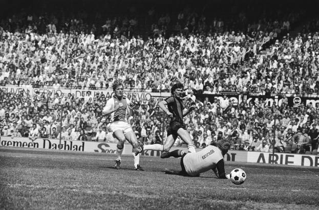 Schwarzes Foto von Fussballspielern in Aktion auf einem Feld mit Zuschauern im Hintergrund und einem Banner mit der Aufschrift "Bundesliga 1978-79 Ajax 1-1 Hannover 96."