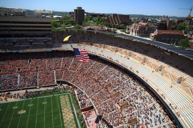 Ein Fußballstadion voller Zuschauer, umgeben von Gebäuden, Bäumen und einem Kran, mit einer Fahne in der Mitte und dem Himmel oben