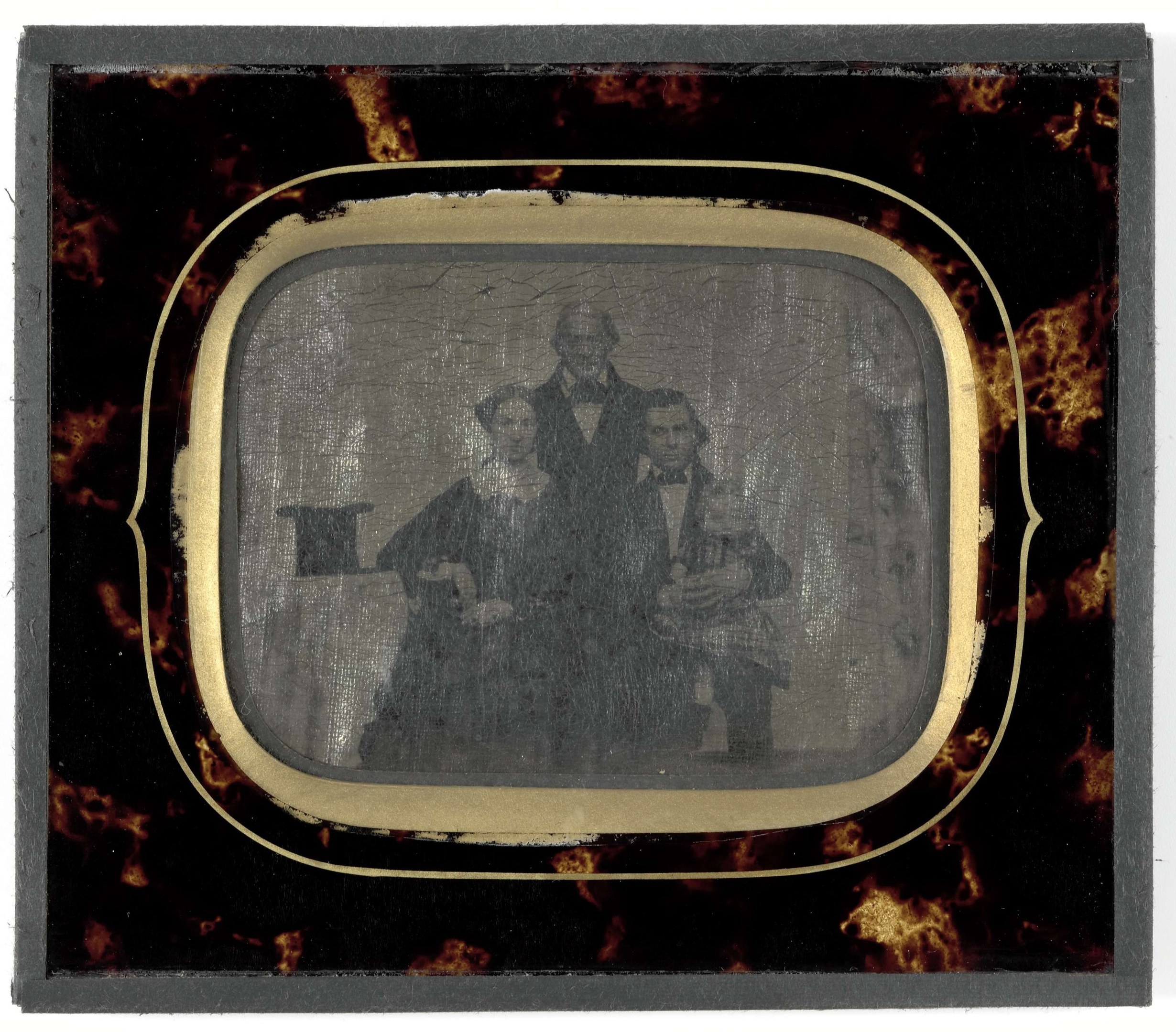 Schwarz-weißes Foto eines Mannes in Anzug und Krawatte und einer Frau in unbekannter Kleidung, die vor einem alten Fernseher stehen, beide mit ernsten Gesichtern.