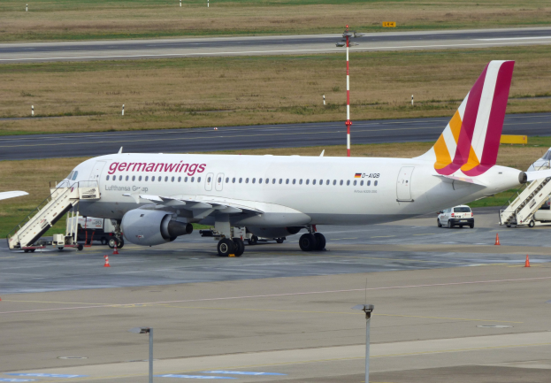Germanwings Airbus A320-200 am Frankfurter Flughafen mit Bodenfahrzeugen, Verkehrskegeln, Pfosten und Gras im Hintergrund.