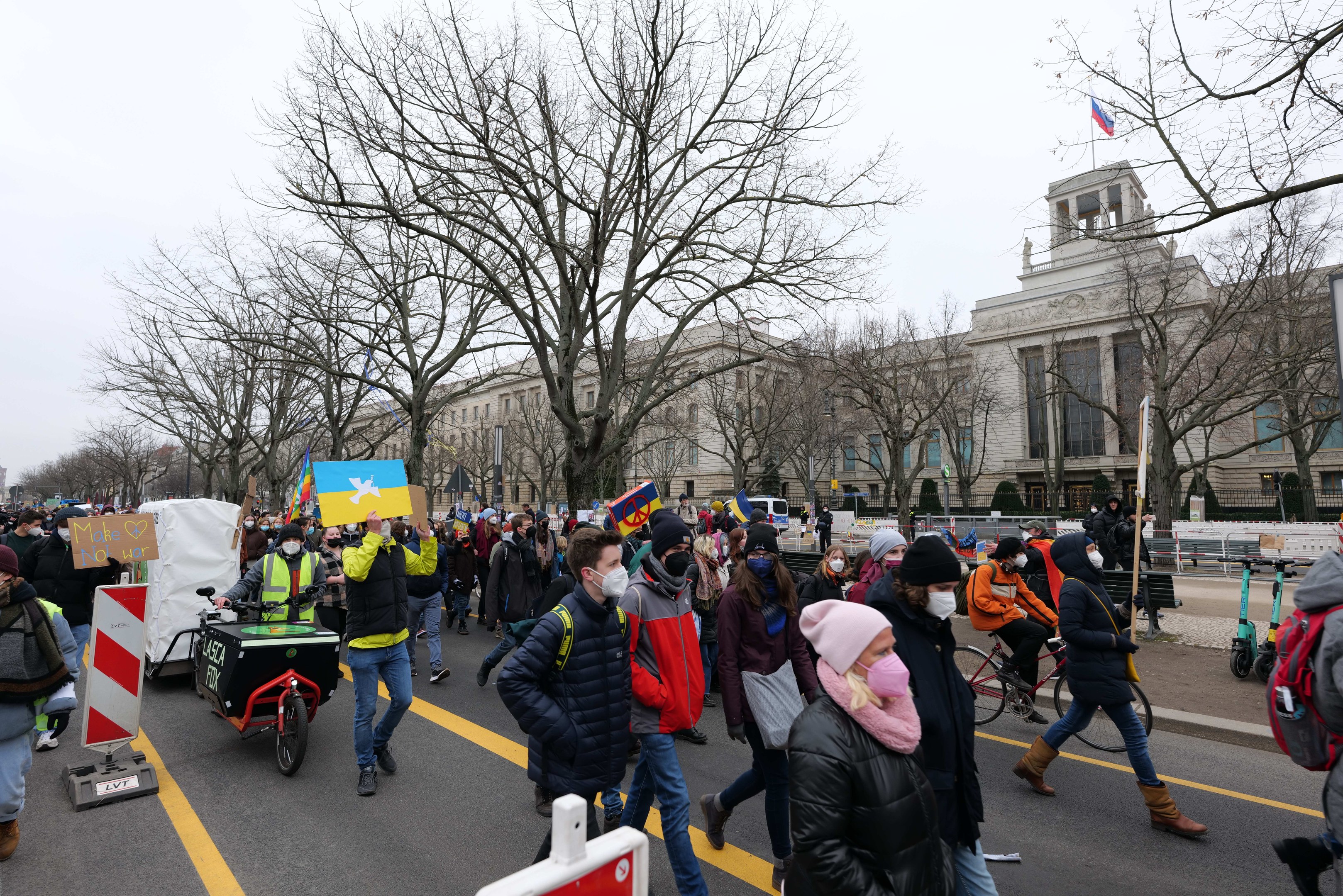 Eine große Gruppe von Menschen marschiert auf einer Stadtstraße demonstrierend, einige halten Schilder und andere fahren Fahrräder, mit Bäumen und einem Gebäude im Hintergrund unter einem klaren blauen Himmel in Washington, D.C. am 21. Januar 2020.