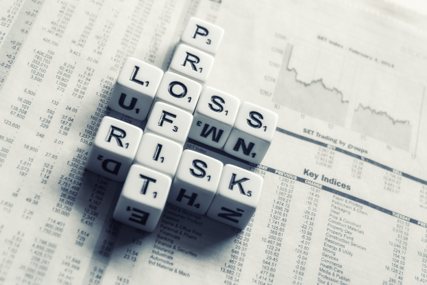 Ein Kreuzworträtsel mit den Wörtern "Verlust", "Risiko" und "Risiko" auf einer Zeitung mit Finanztext und -zahlen.