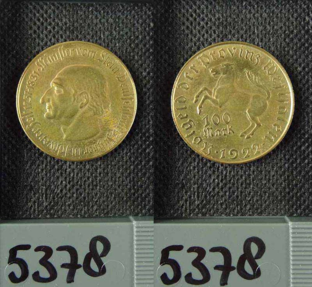 Zwei Goldmünzen aus Deutschland im Jahr 1922, jeweils mit einer Denomination von 100 Mark, werden auf einer schwarzen Oberfläche mit Zahlen unten platziert.