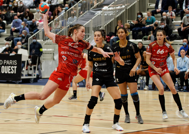 Eine Gruppe von Frauen beim Handballspielen auf einem Feld während der Handball-Weltmeisterschaft 2019 in Paris mit Zuschauern im Hintergrund.