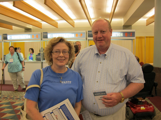 Menschen, die auf einem Boden mit einem Rollstuhl und einer Wand im Hintergrund, Decke und Lichter über ihnen stehen.