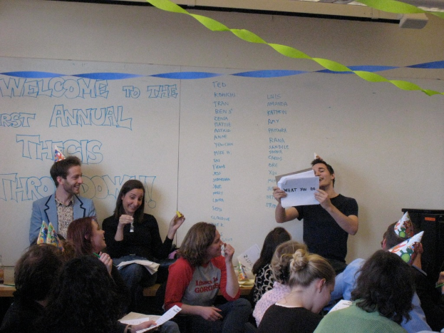 Eine Gruppe von Menschen feiert ihren ersten Jahrestag der Abschlussarbeit mit Bändern auf dem Dach und einigen Personen mit Mützen.