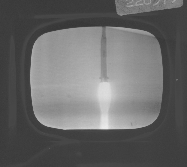 Schwarzes und weißes Foto eines Fernseherbildschirms, der eine Raketenstarts zeigt, mit Text oben.