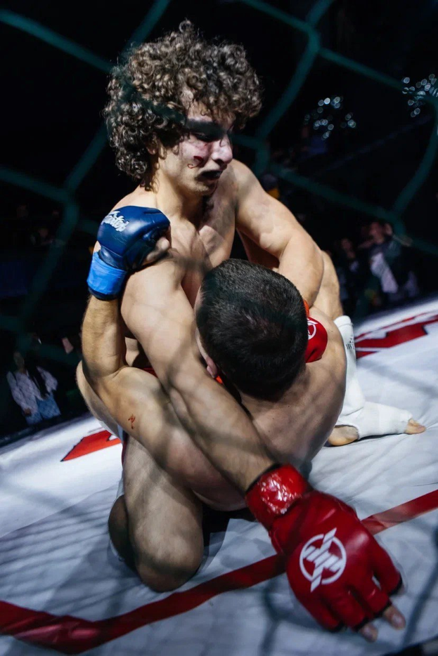 Zwei Männer in einem MMA-Ring im Kampf gegeneinander, einer setzt einen mächtigen Tritt