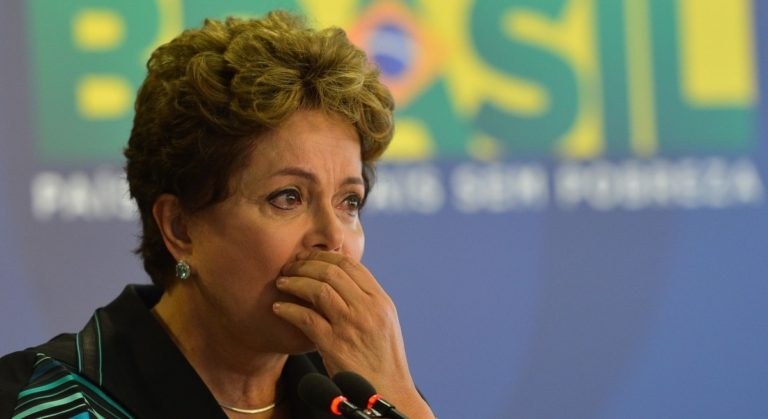 Brasiliens Präsidentin Dilma Rousseff bei einer Pressekonferenz in Rio de Janeiro vor einer Tafel mit Text und mehreren Mikrofonen.