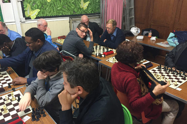 Eine Gruppe von Menschen, die um einen Tisch sitzen und Schach spielen.