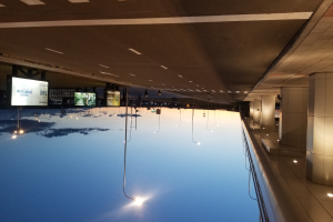 Ein Hallenbad mit Säulen auf der rechten Seite und einer Decke mit Lampen, mit Bildschirmen im Hintergrund.