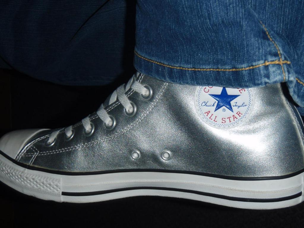 Ein Schuh mit Text und Schnürsenkeln, mit dem Rand von Jeans oben rechts auf einem dunklen Hintergrund.