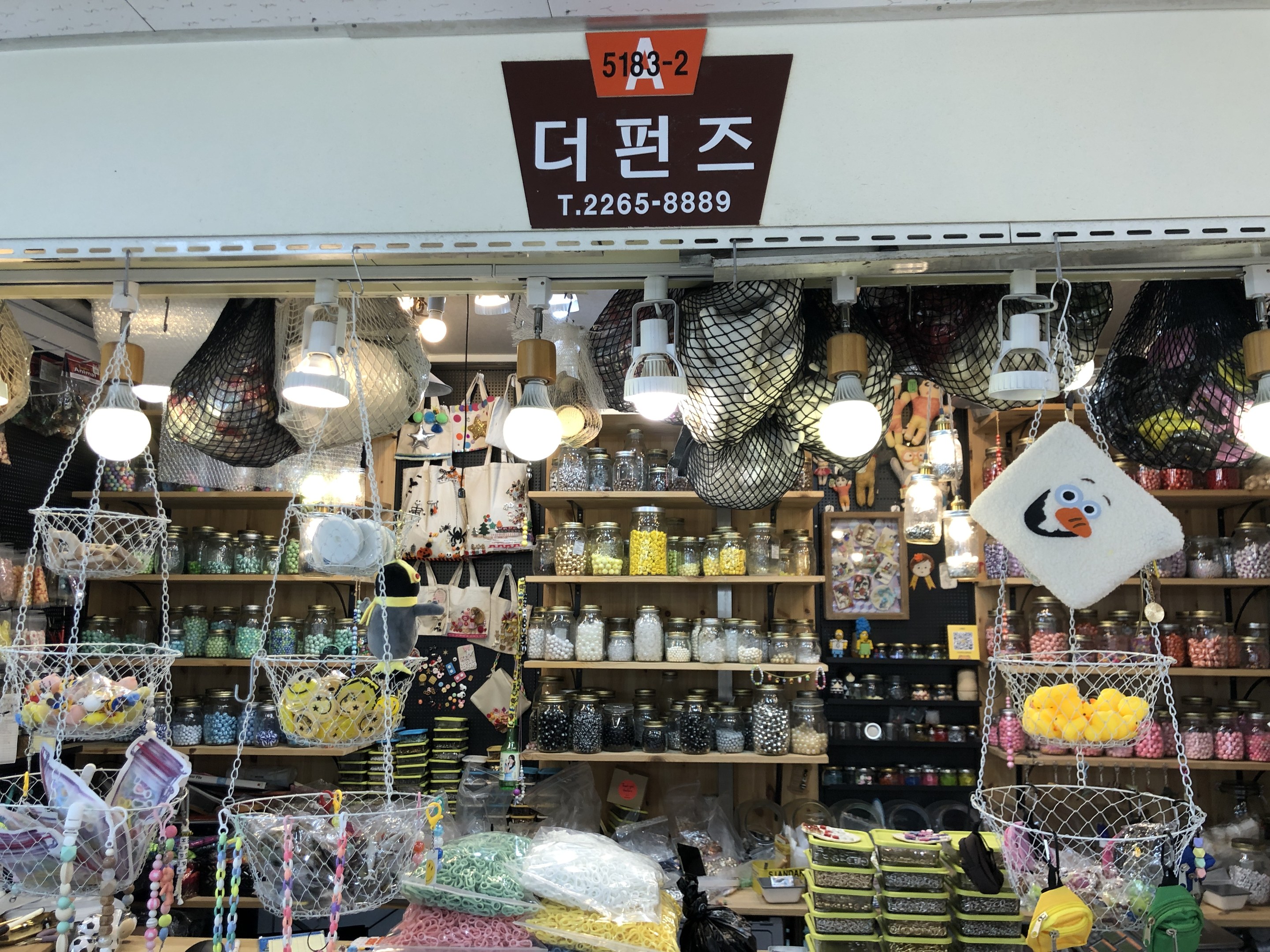 Ein unordentlicher Laden in Seoul, der verschiedene Gegenstände wie Körbe, Lichter, Flaschen und Spielzeuge auf Regalen ausstellt, mit einem Schild öben, das anzeigt, dass es einer der besten koreanischen Läden ist.