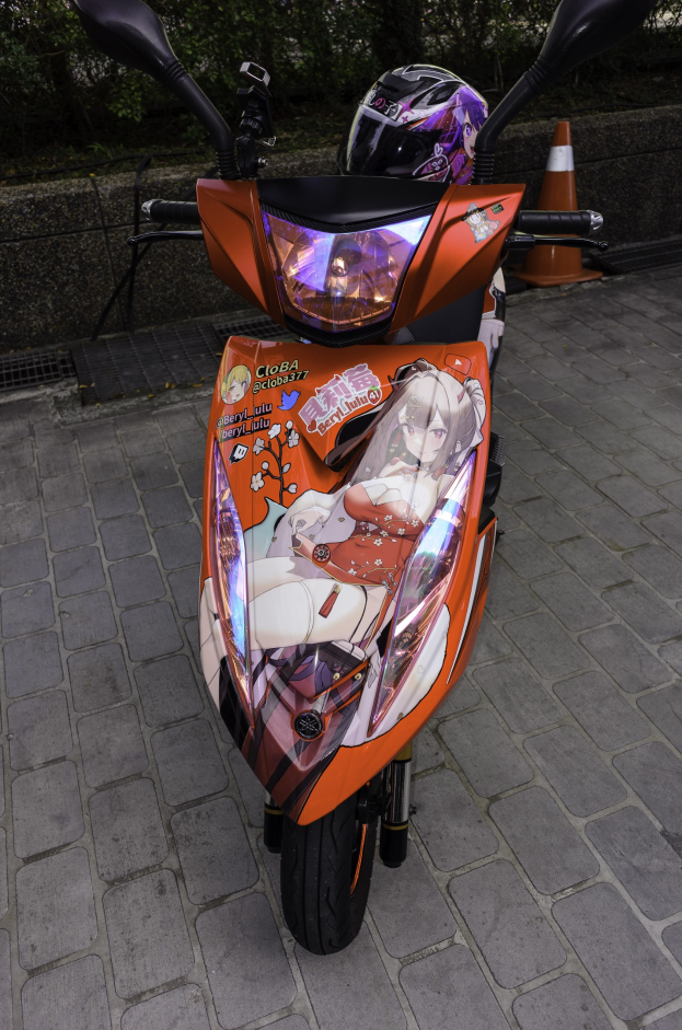 Ein oranger E-Scooter, der auf der Seite einer Straße geparkt ist, mit einem Helm darauf, einem Verkehrskegel, einer Wand und mehreren Bäumen im Hintergrund.