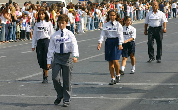 Eine Gruppe von Menschen, die auf einer Straße gehen und Abzeichen auf ihren Hemden tragen, mit einer großen Menge drumherum.