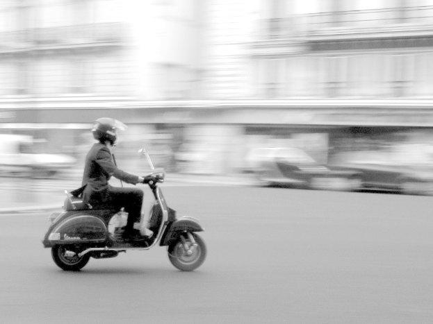 Eine Person f√§hrt mit einem Roller auf der Stra√Ÿe.