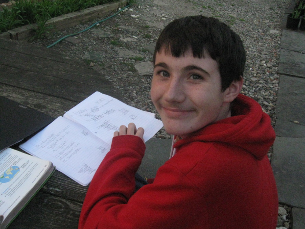 Eine Person in einer roten Jacke sitzt vor einer Sammlung von B├╝chern.