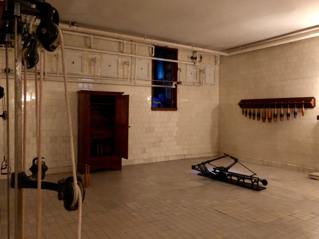 Ein unordentlicher Raum im ehemaligen Gefängnis St. Louis mit Seilen, Maschinen und anderem Equipment, mit einem Schrank, Fenster und einer Deckenlampe.