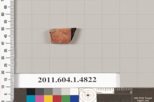 Ein kleines Tonstück neben einem Lineal mit Zahlen, Text und Farbmustern auf einer weißen Oberfläche.