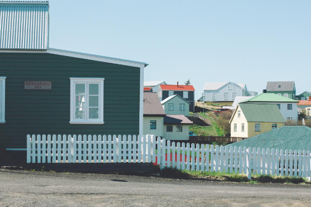 Eine Reihe von Häusern mit einem klaren Himmel darüber und grasigem Land dazwischen.