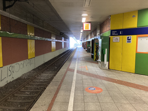 Ein Bahnsteig in Berlin, Deutschland, bekannt als Berlin Hauptbahnhof, mit einem Zug auf den Schienen, beleuchtet von Deckenlampen, Graffiti an der linken Wand und ein paar Gegenständen auf der rechten Seite.
