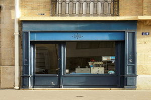 Blaue Tür und Fenster an einem Gebäude mit einem Rohr an der Wand und einem Geländer oben auf einer Straße.