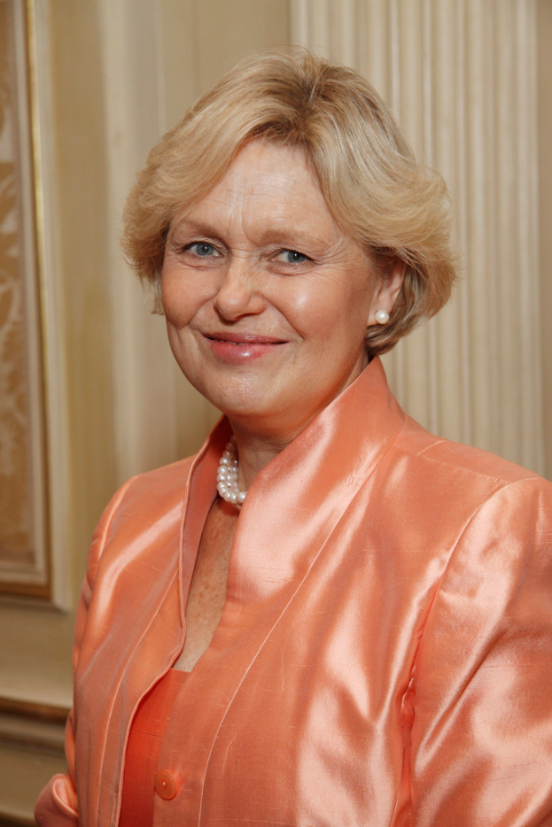 Eine Frau in einem orangefarbenen Kleid mit einem Foto im Hintergrund.