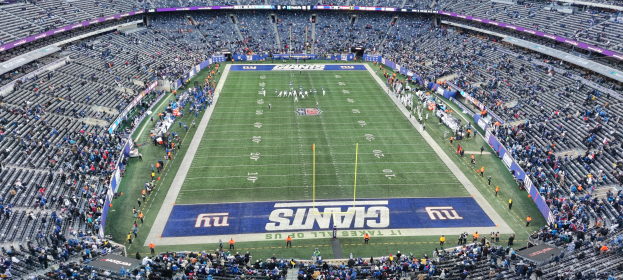 Ein Fußballstadion voller Zuschauer, Spieler, Pfosten und Schilder mit Text, alle auf Stühlen sitzend, die eine lebendige Atmosphäre schaffen.