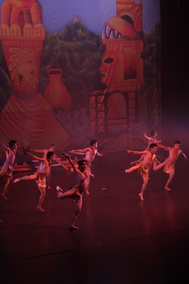 Leute in Kostümen, die auf einer Bühne mit einem Vorhang im Hintergrund auftreten.