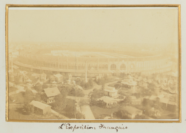 Altes Schwarz-Weiß-Foto eines Stadions in zentraler Lage in einer Stadt, umgeben von Gebäuden, Bäumen und Strommasten, mit Text unten.