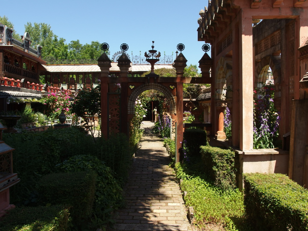 Ein Wohngebiet mit Häusern, umgeben von Bäumen und Pflanzen mit bunten Blumen.