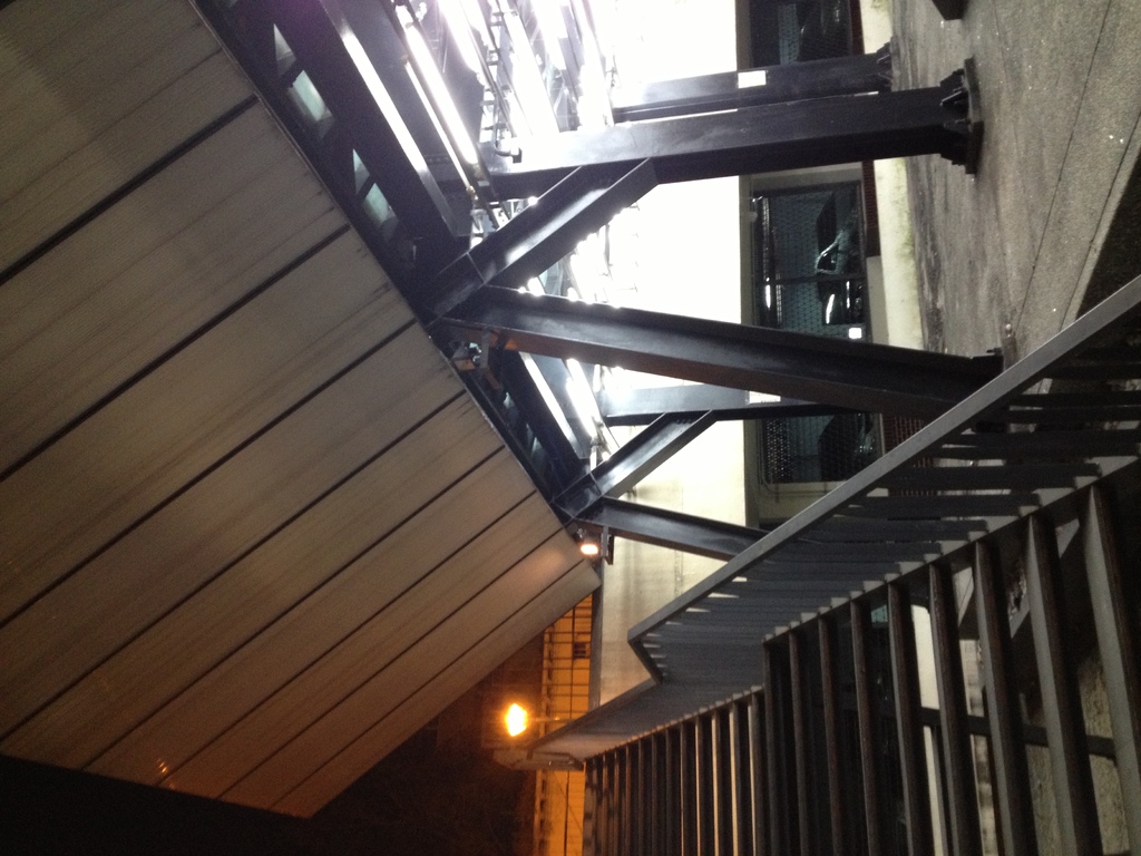 Treppen mit Geländern in der unteren rechten Ecke, Säulen auf der rechten Seite des Bodens, Autos in Gebäuden hinter Säulen, Lampen und Decke auf der linken Seite.