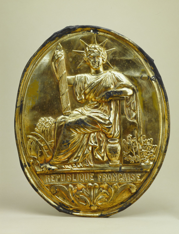 Goldenes rundes Schild mit einer erhabenen Statue der Freiheitsstatue-Entwurf mit eingraviertem Text, vor einem weißen Hintergrund.