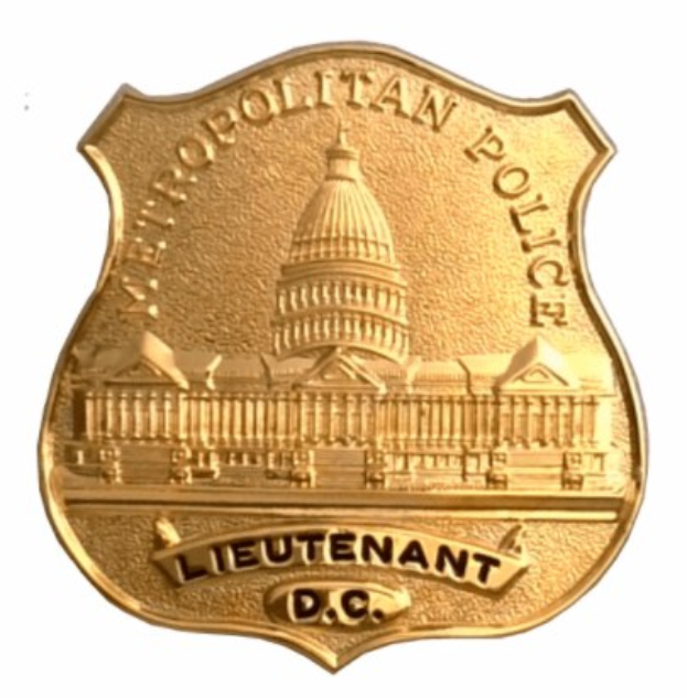 Goldenes Polizeidienstabzeichen mit "Leutnant DC" eingraviert, mittig auf einem weißen Hintergrund.