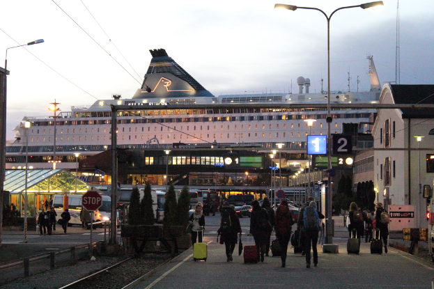 Eine belebte Straße mit Menschen, die Taschen tragen und an Polen und Gebäuden vorbeigehen.