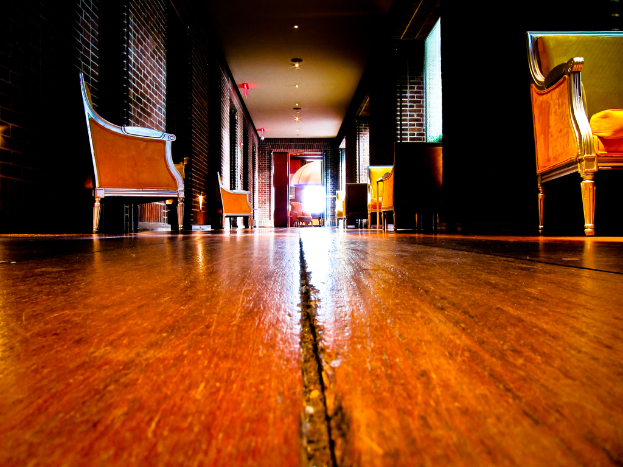 Ein Weihnachtsbaum auf einer Straße mit Menschen darauf, flankiert von zwei Fahnenmasten, mit beleuchteten Gebäuden im Hintergrund.