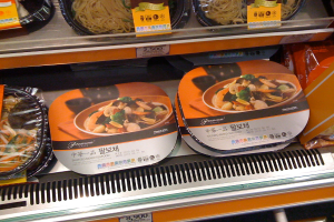 Lebensmittelboxen in Regalen mit Preisaufklebern.