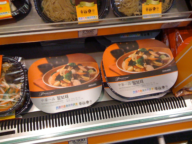 Lebensmittelboxen in Regalen mit Preisaufklebern.