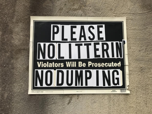 Schwarzes und weißes Schild an einem Gebäude mit der Aufschrift "Bitte Kein Müll Verunreiniger Werden Bestraft Keine Ablagerung."
