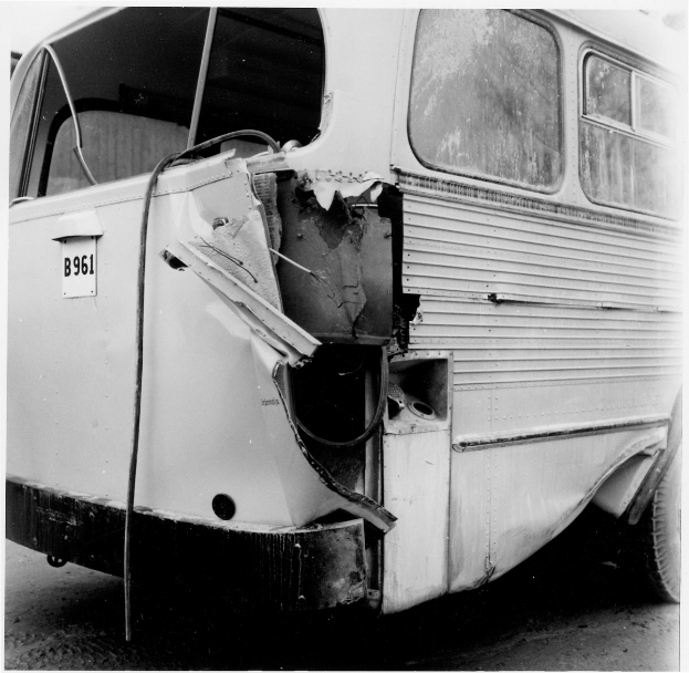 Schwarz-weißes Foto eines Busses mit schwerer Frontschaden nach einem Autounfall, positioniert auf der Straße.