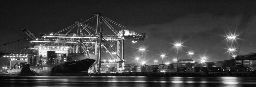 Ein Schiffbauwerk mit Metallkonstruktionen, Laternen, Containern und Schiffen.