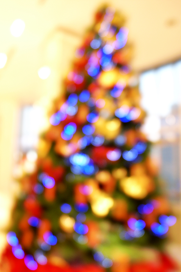 Eine unscharfe Innenaufnahme mit einem Weihnachtsbaum, der mit Lichtern und Schmuck verziert ist.