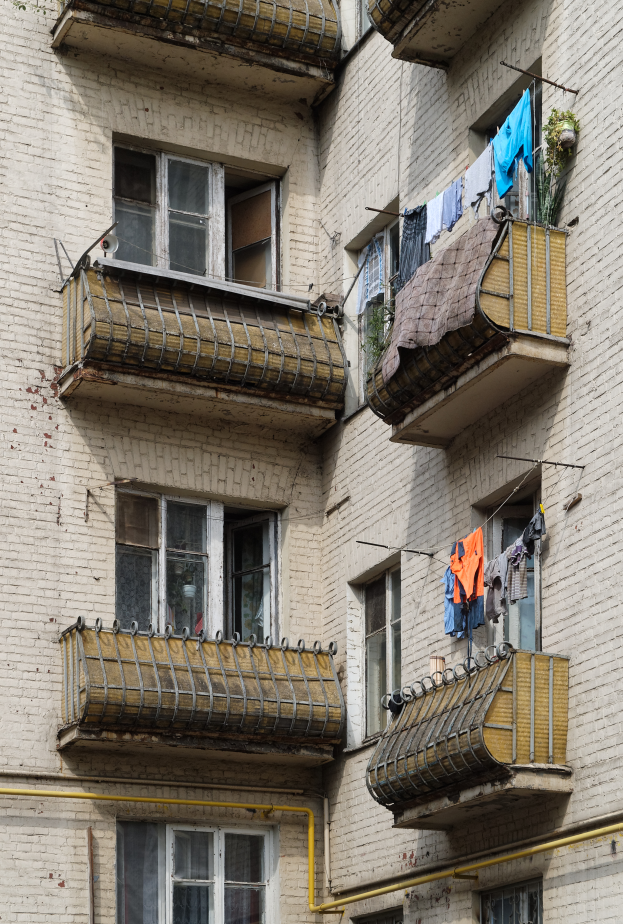 Ein Wohnhaus mit Fenstern, Balkonen, Wäsche zum Trocknen und Rohren an der Seite.