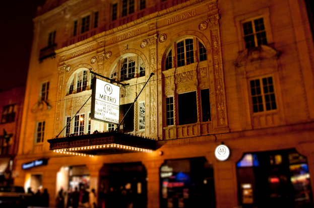Ein gelbes Gebäude mit Geschäften unten und einem weißen Schild mit der Aufschrift "Metro" davor.