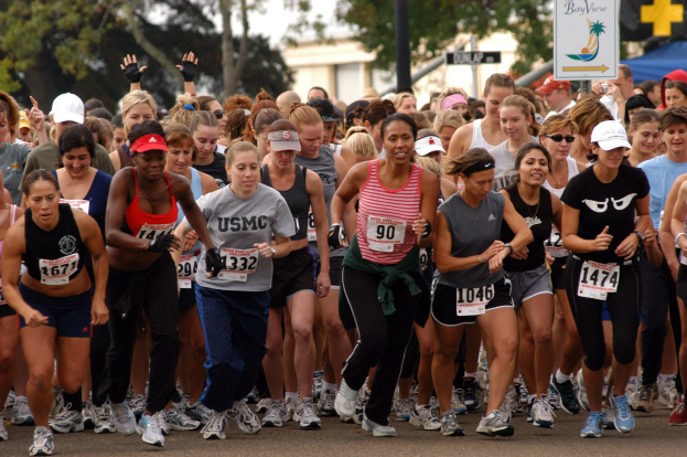Gruppe von Frauen beim Marathon auf einer von Bäumen gesäumten Straße mit unscharfem Hintergrund
