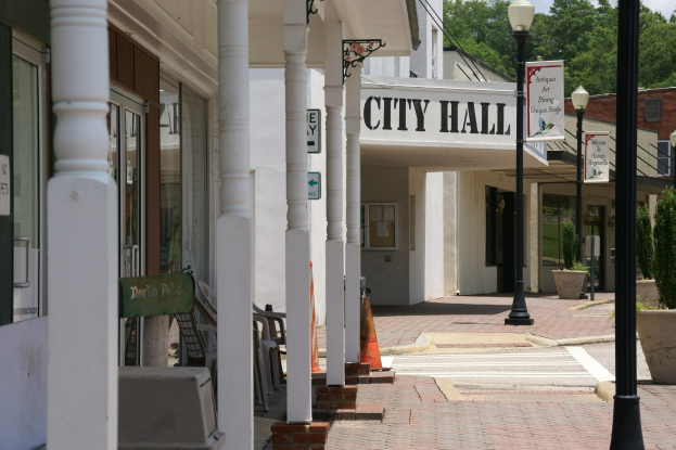 Rathaus mit umliegenden Gebäuden, Straßeninfrastruktur, Fahrzeugen und Grünflächen bei bewölktem Himmel.