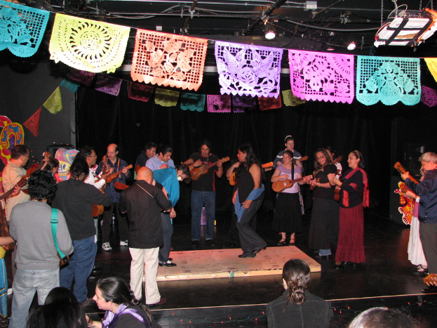 Menschen mit Musikinstrumenten stehend im Zentrum, mit Dekorationen und Lichtern oben und einem Boden unten.