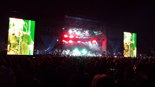 Ein Konzertbild mit einer Menge unten und einem großen Bildschirm links und einem kleineren rechts.