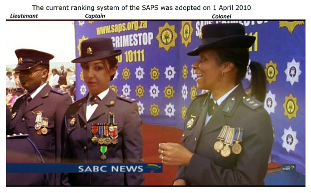 Gruppe von Menschen in Uniformen und Hüten mit einem Banner und Text, der "Das aktuelle Rankingsystem der SAP wurde am 1. April 2010 übernommen" an der Spitze und unten angibt.